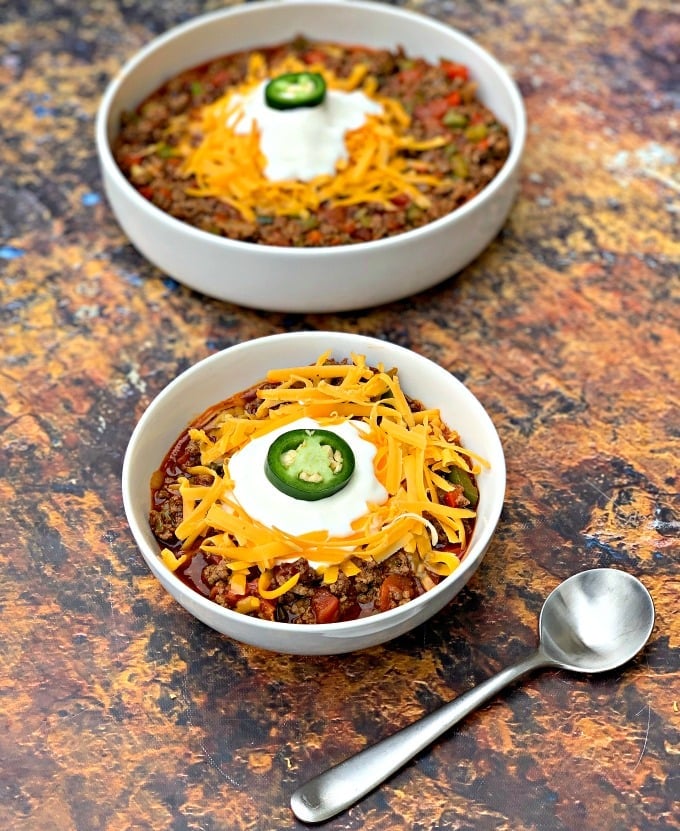 keto beef chili with shredded cheese in white bowls