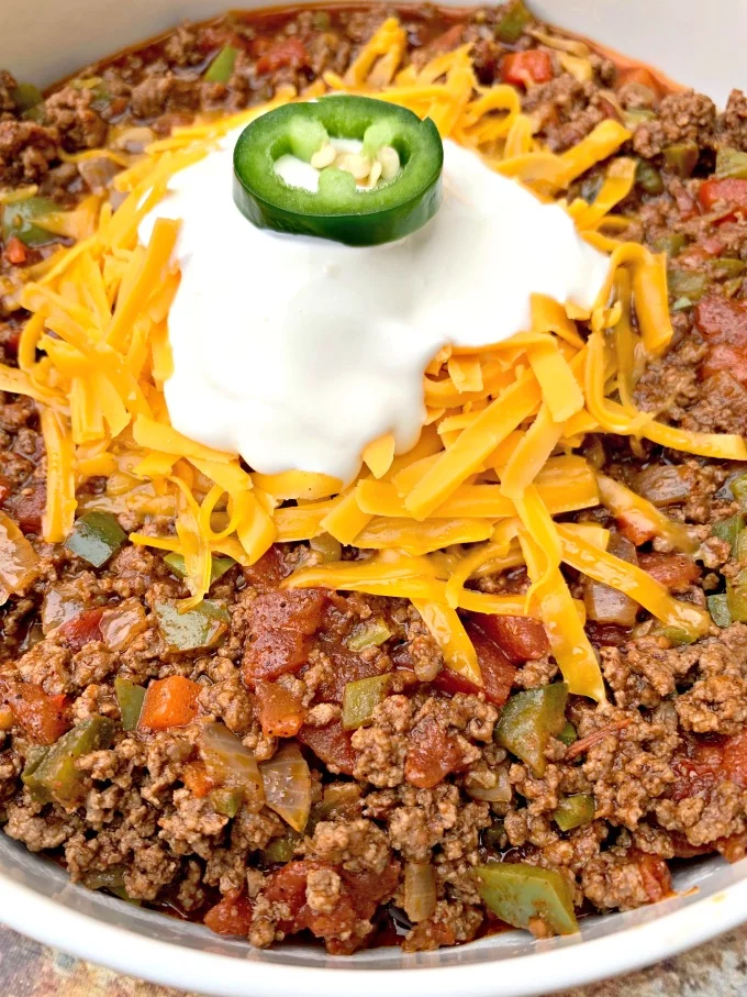 close up of keto beef chili with sour cream and shredded cheese