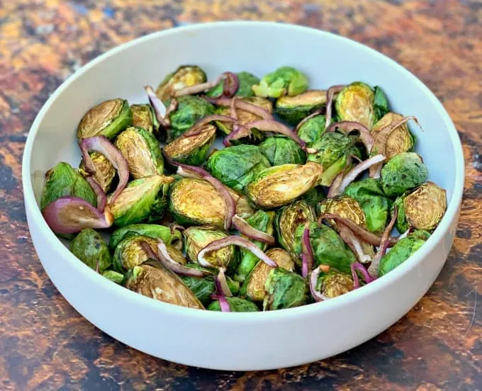air fryer balsamic brussels sprouts with red onions in a white bowl