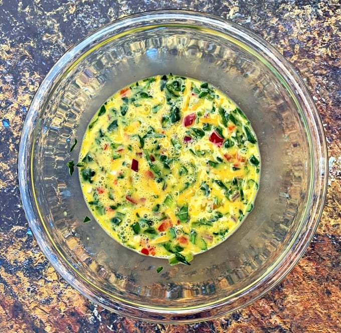 eggs, chopped veggies, and shredded cheese in a glass bowl