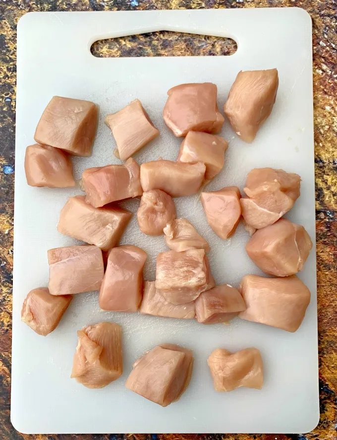 raw chicken cut into cubes on a cutting board