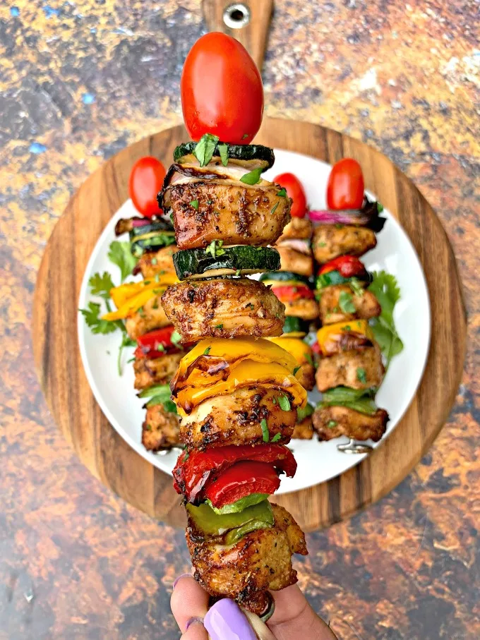 person holding air fryer grilled chicken kebobs with a skewer