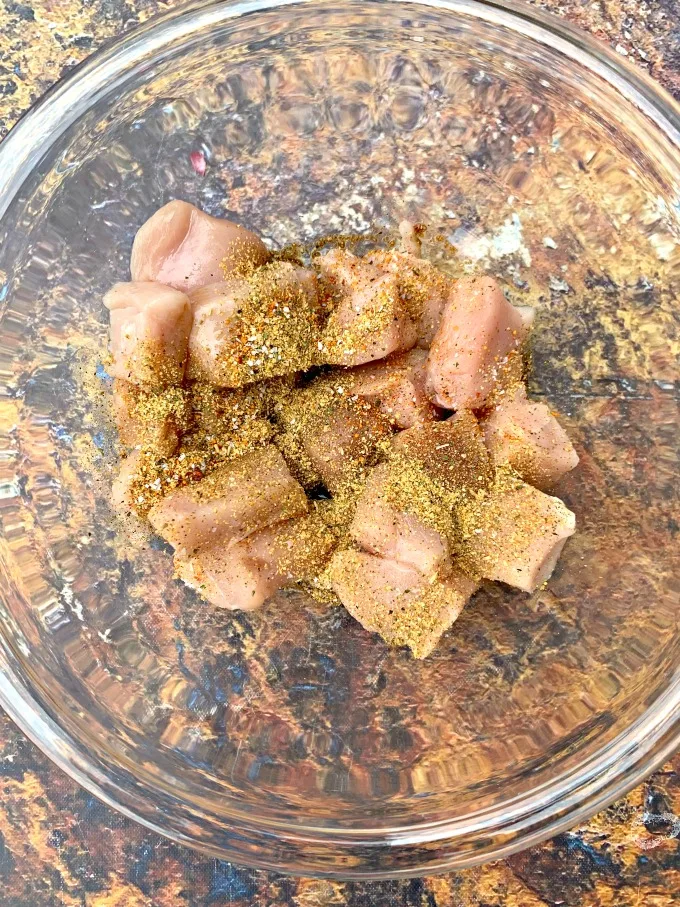 raw chicken in a glass bowl with seasoning