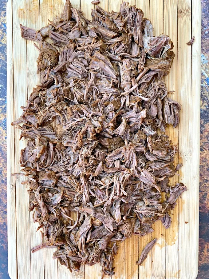 instant pot keto low carb barbacoa beef with cilantro and limes on a cutting board