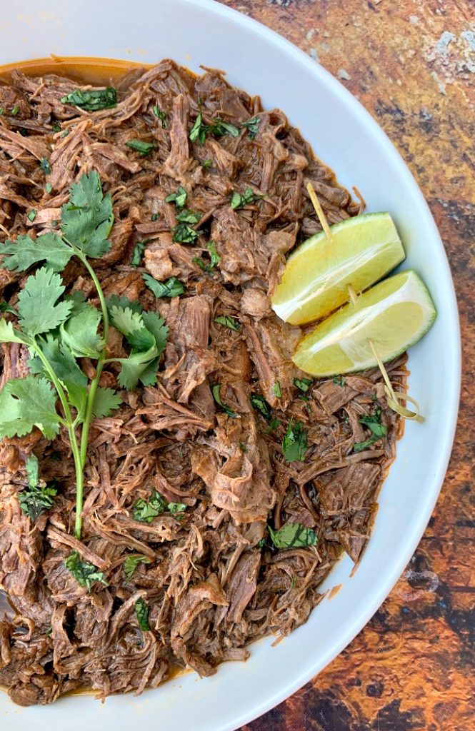 instant pot keto low carb barbacoa beef with cilantro and limes in a white bowl