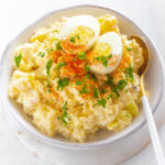 Instant Pot potato salad in a white bowl with boiled eggs and sprinkled with paprika