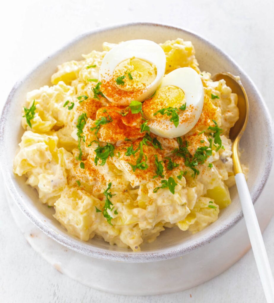 Instant Pot potato salad in a white bowl with boiled eggs and sprinkled with paprika