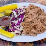 instant pot pulled pork on a plate with cabbage and pickles