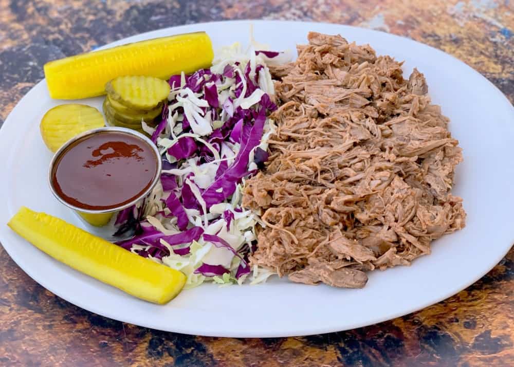 instant pot pulled pork on a plate with cabbage and pickles