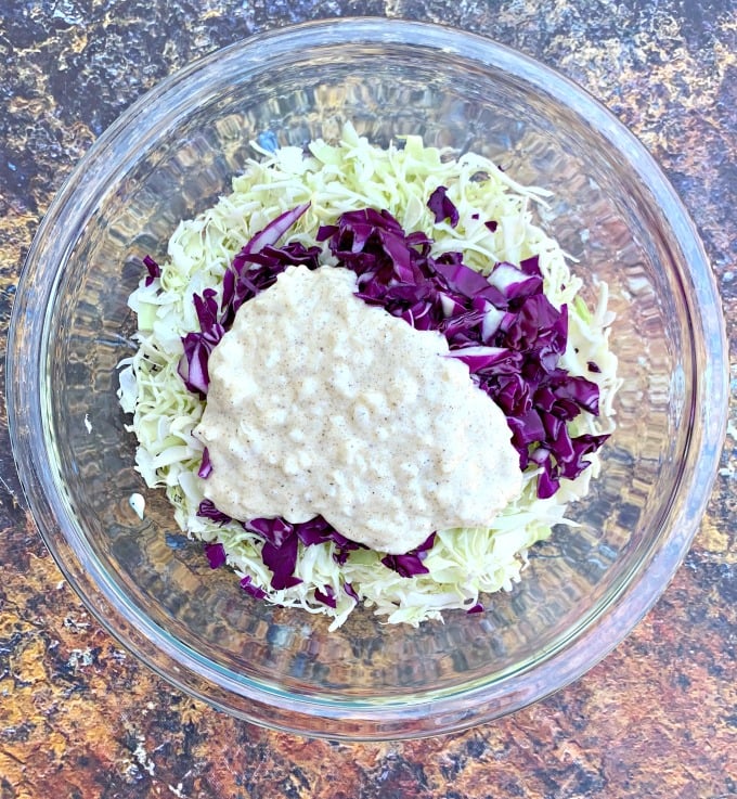 keto low carb coleslaw in a glass bowl with liquid mixture on top