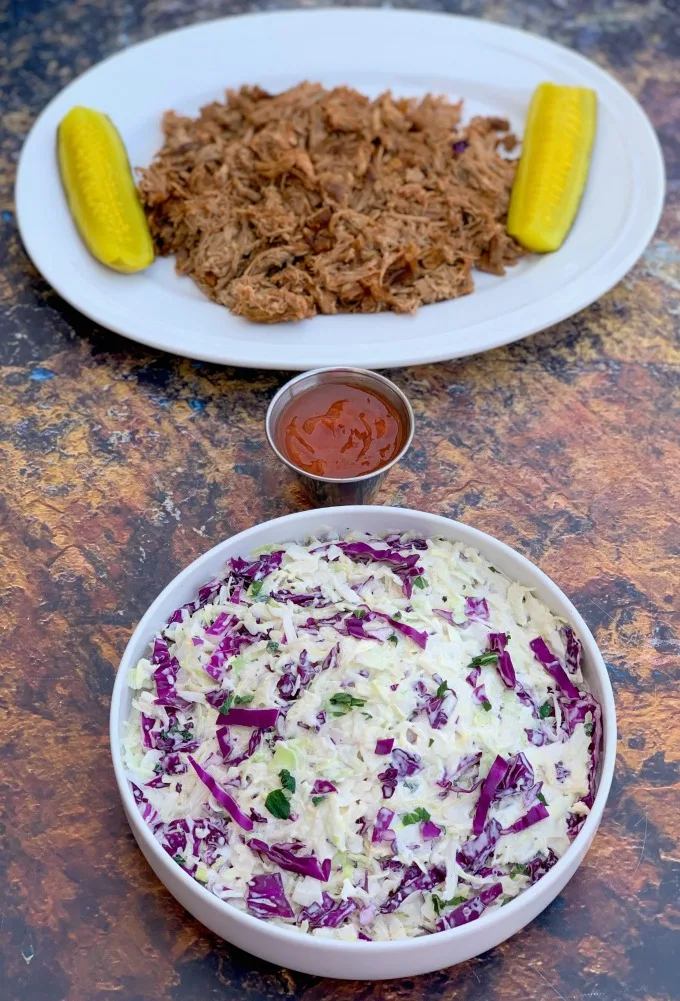 keto low carb coleslaw in a white bowl alongside pulled pork and pickles