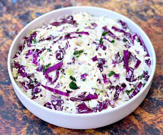 keto low carb coleslaw in a white bowl alongside pulled pork and pickles