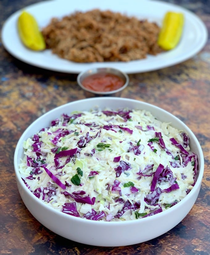 keto low carb coleslaw in a white bowl alongside pulled pork and pickles