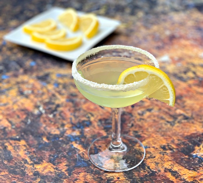 keto low carb lemon drop cocktail in a martini glass with lemon wedges on a white plate