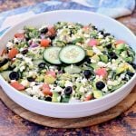 keto zucchini noodles pasta salad in a white bowl with tomatoes, olives, cucumbers, feta cheese, and red onions