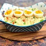 keto low carb potato salad with boiled eggs in a blue bowl on a wooden pizza paddle board