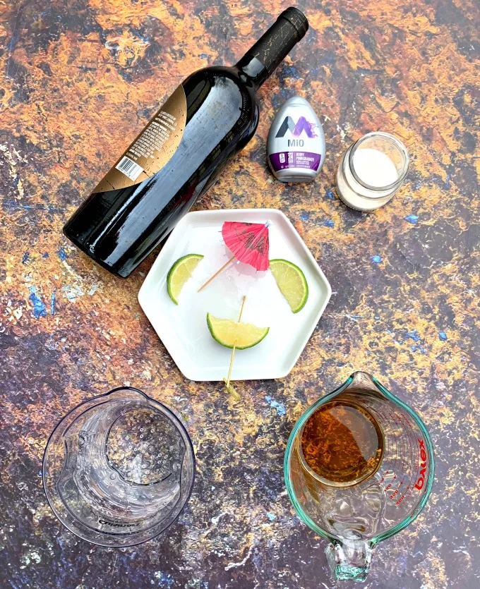 red wine, brandy, club soda, and limes on a flat surface