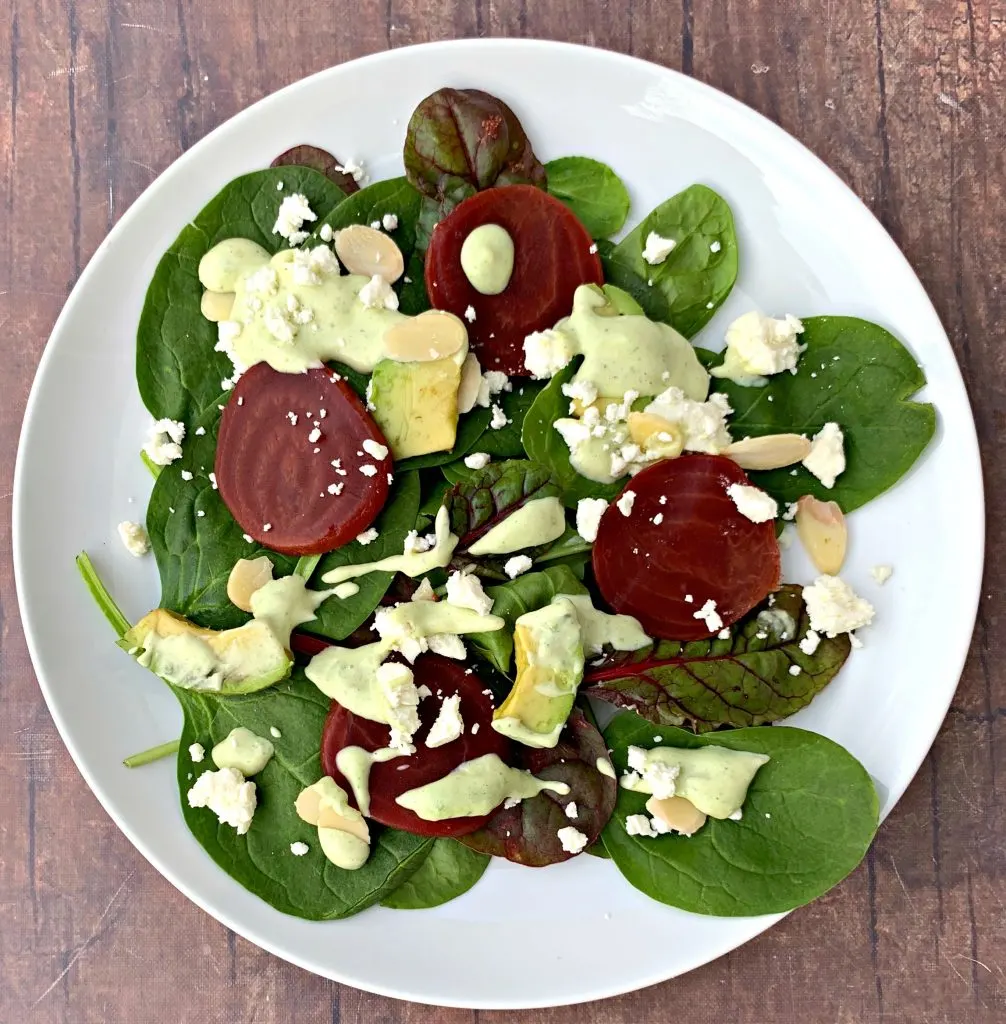 green goddess beet salad on a white plate with dressing