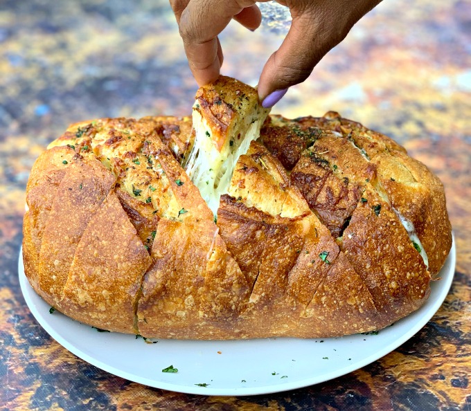 person pulling a piece of air fryer pull apart garlic cheese bread