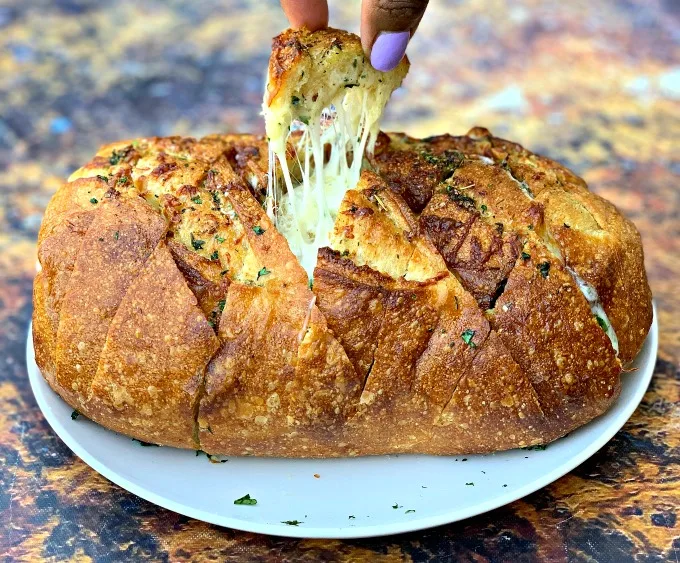 person pulling a piece of air fryer pull apart garlic cheese bread