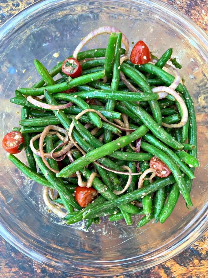 cold green bean salad with tomatoes and feta cheese in a glass bowl