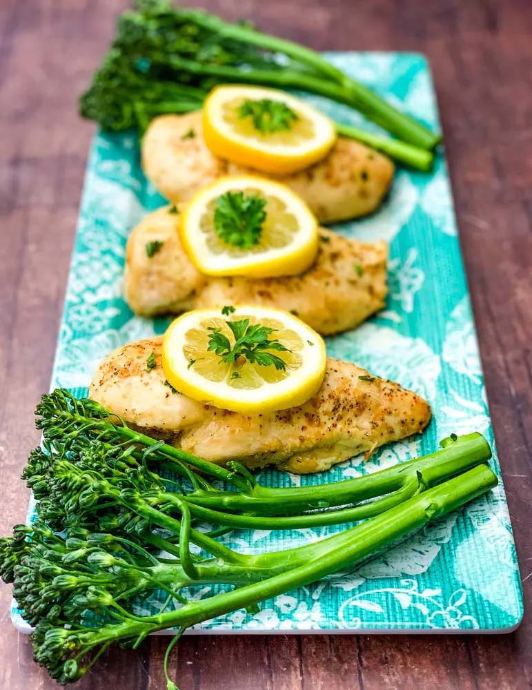 air fryer chicken breast on a blue plate with broccoli and lemons