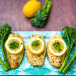 air fryer chicken breast on a blue plate with broccoli and lemons