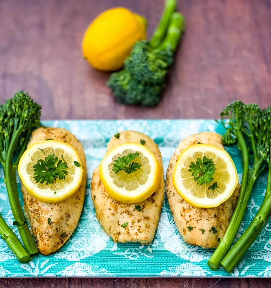 air fryer chicken breast on a blue plate with broccoli and lemons