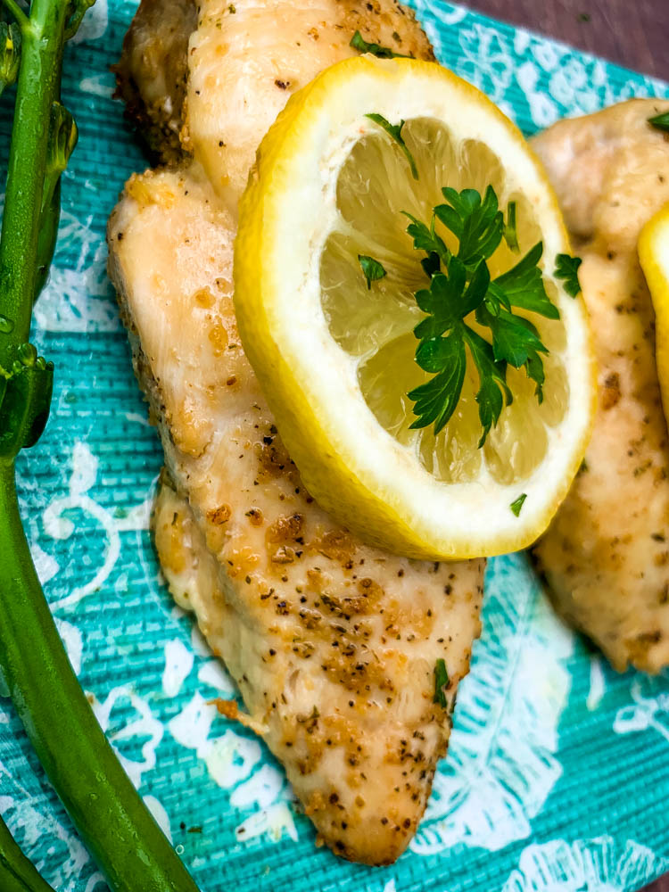 air fryer chicken breast on a blue plate with broccoli and lemons