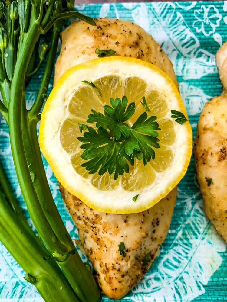 air fryer chicken breast on a blue plate with broccoli and lemons