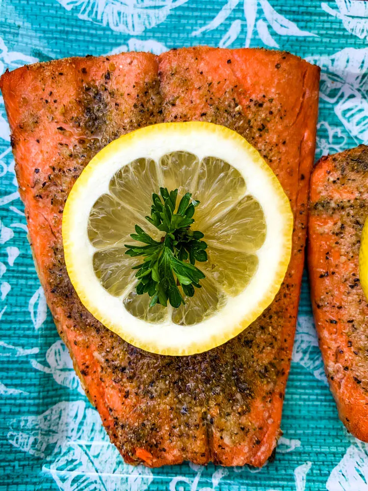 air fryer salmon on a blue plate with a fresh lemon size