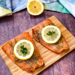 air fryer salmon on a wooden board with a fresh lemon size