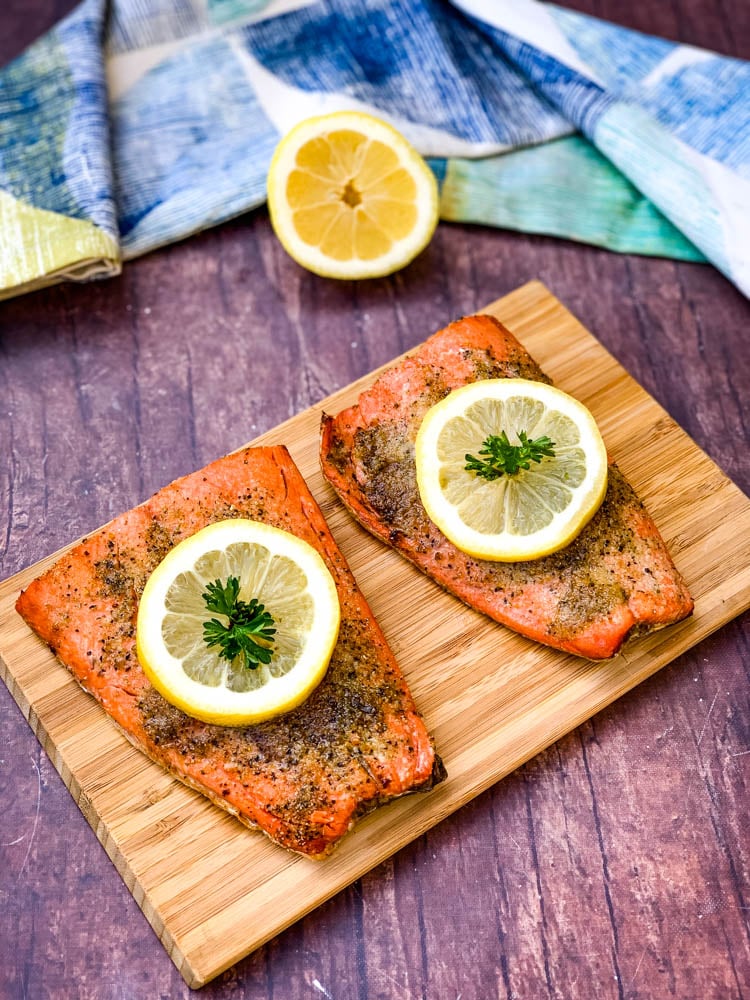 air fryer salmon on a wooden board with a fresh lemon size