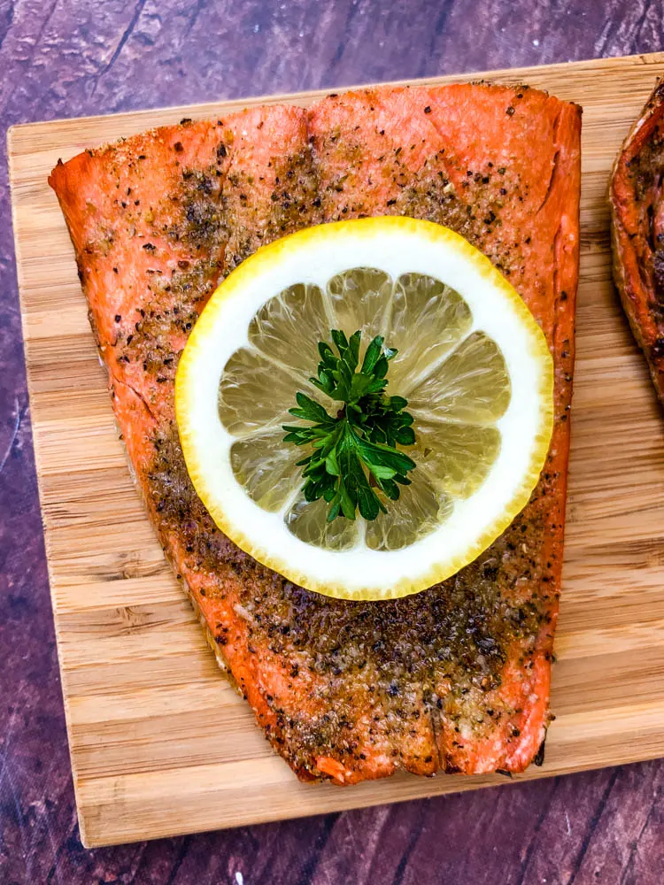 air fryer salmon on a wooden board with a fresh lemon size