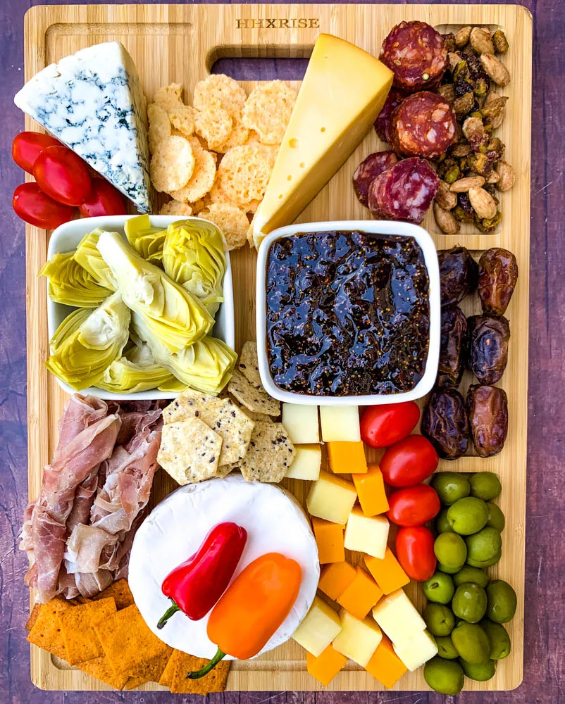 charcuterie board with artichokes, fig spread, cheese, and meat