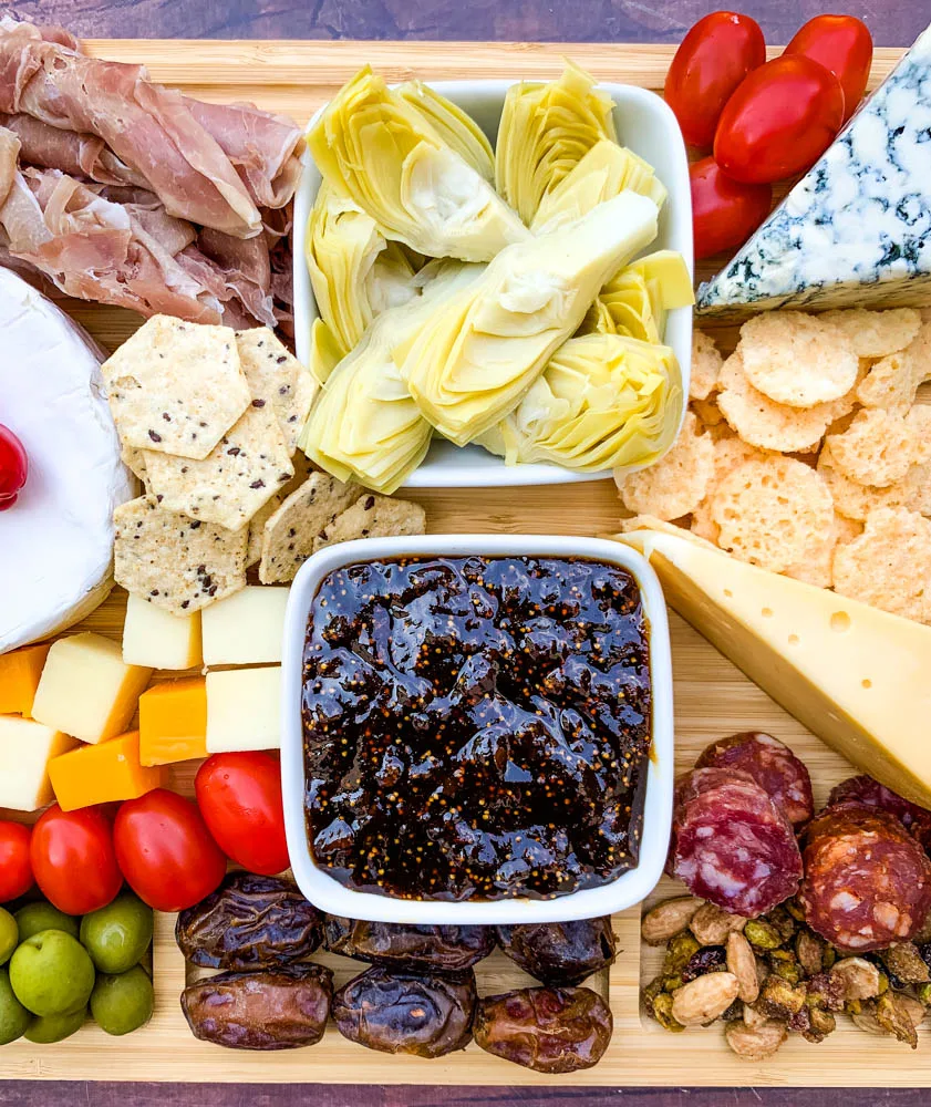 charcuterie board with artichokes, fig spread, cheese, and meat