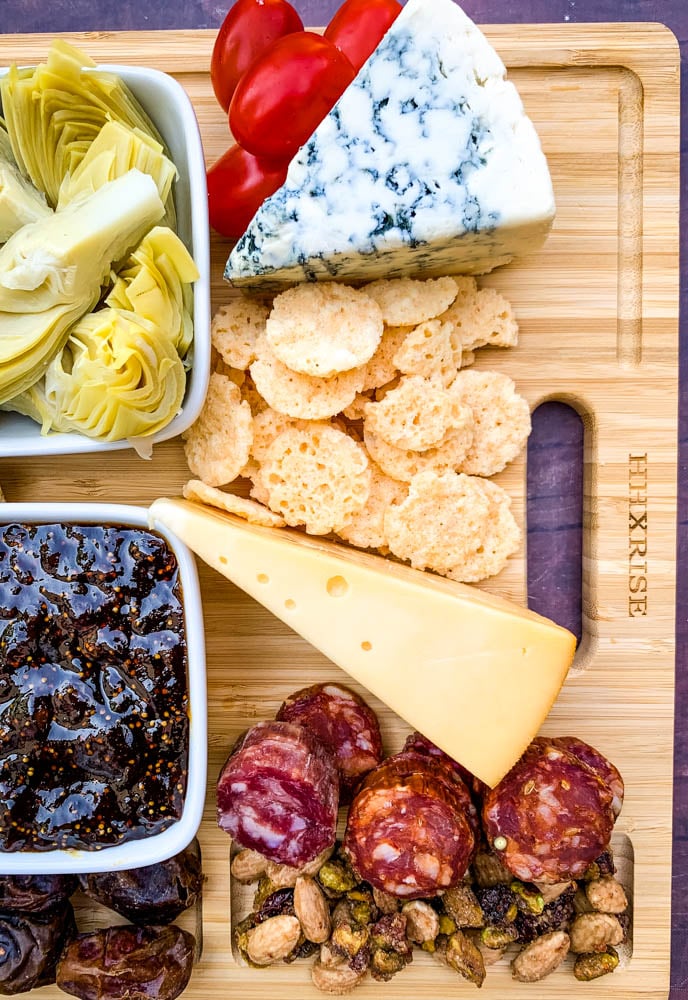 charcuterie board with artichokes, fig spread, cheese, and meat