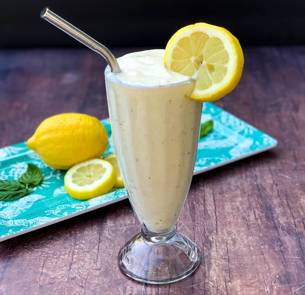 chickfila frosted lemonade in a glass cup garnished with a lemon and straw