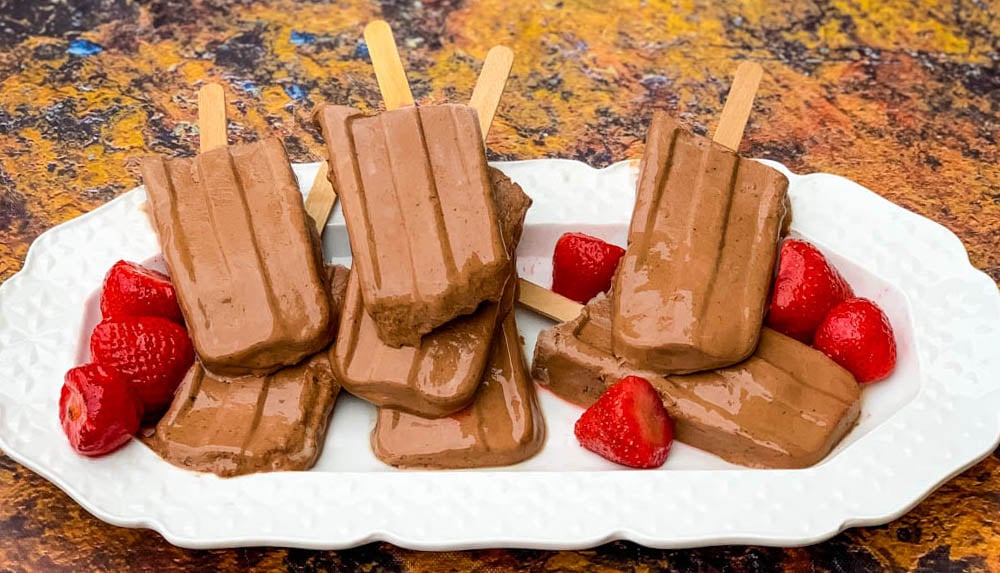 keto low fudge popsicle bars on a white plate with strawberries
