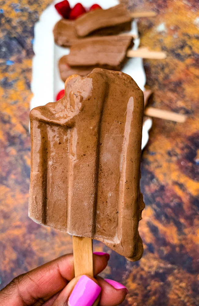 person holding keto low carb fudge popsicle in hand