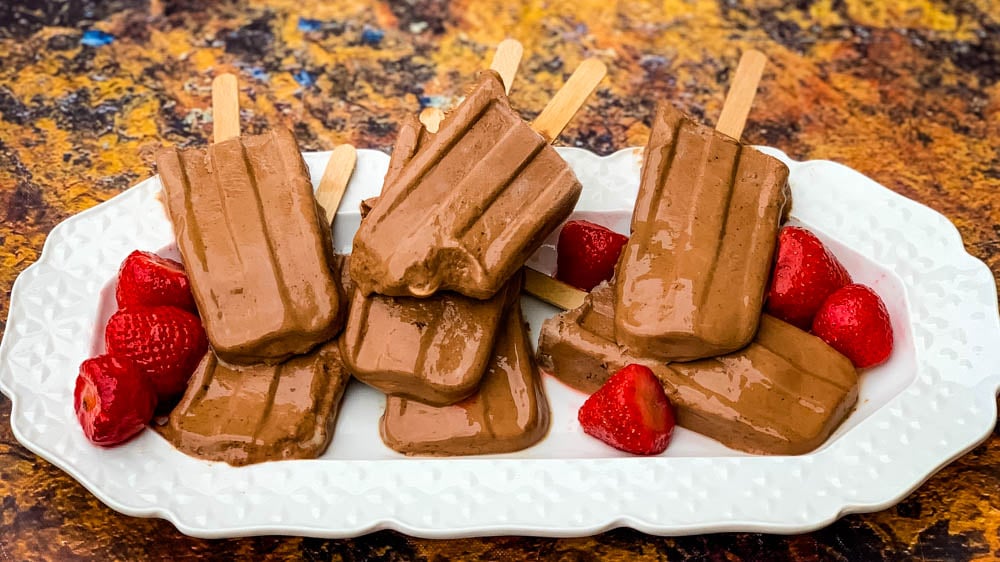 keto low fudge popsicle bars on a white plate with strawberries