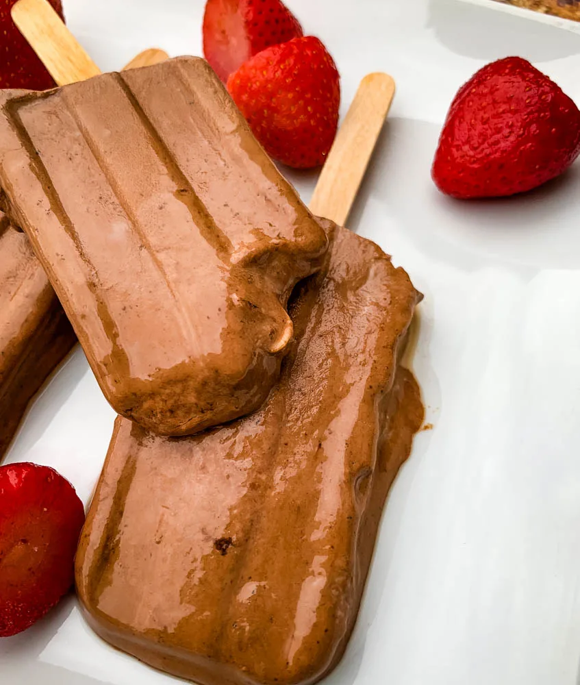 keto low fudge popsicle bars on a white plate with strawberries