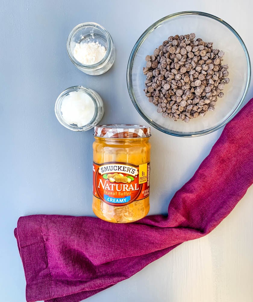 natural peanut butter, chocolate chips, coconut oil, and confectioner's sweetener on a flat surface