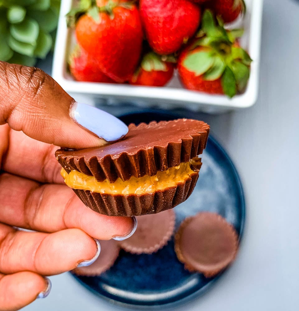 person holding keto low carb peanut butter cup with strawberries in the background