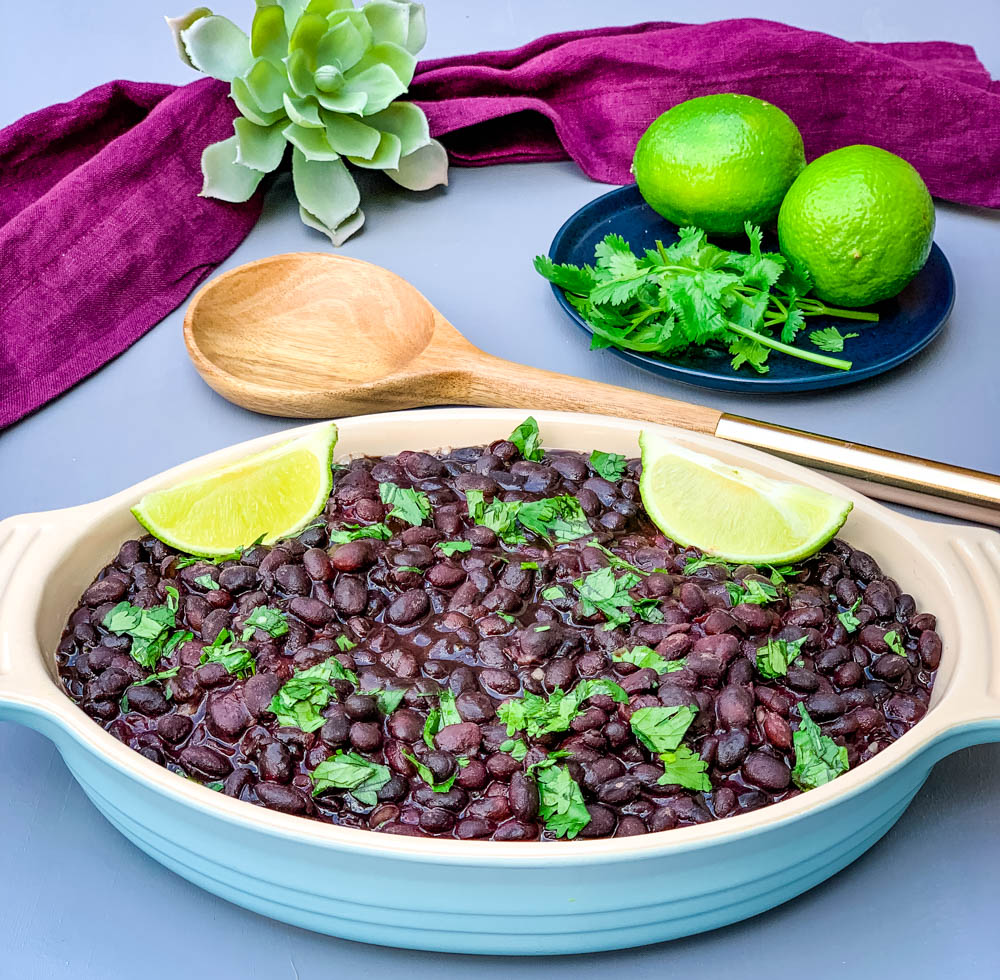 instant pot black beans in a blue bowl with cilantro and lime