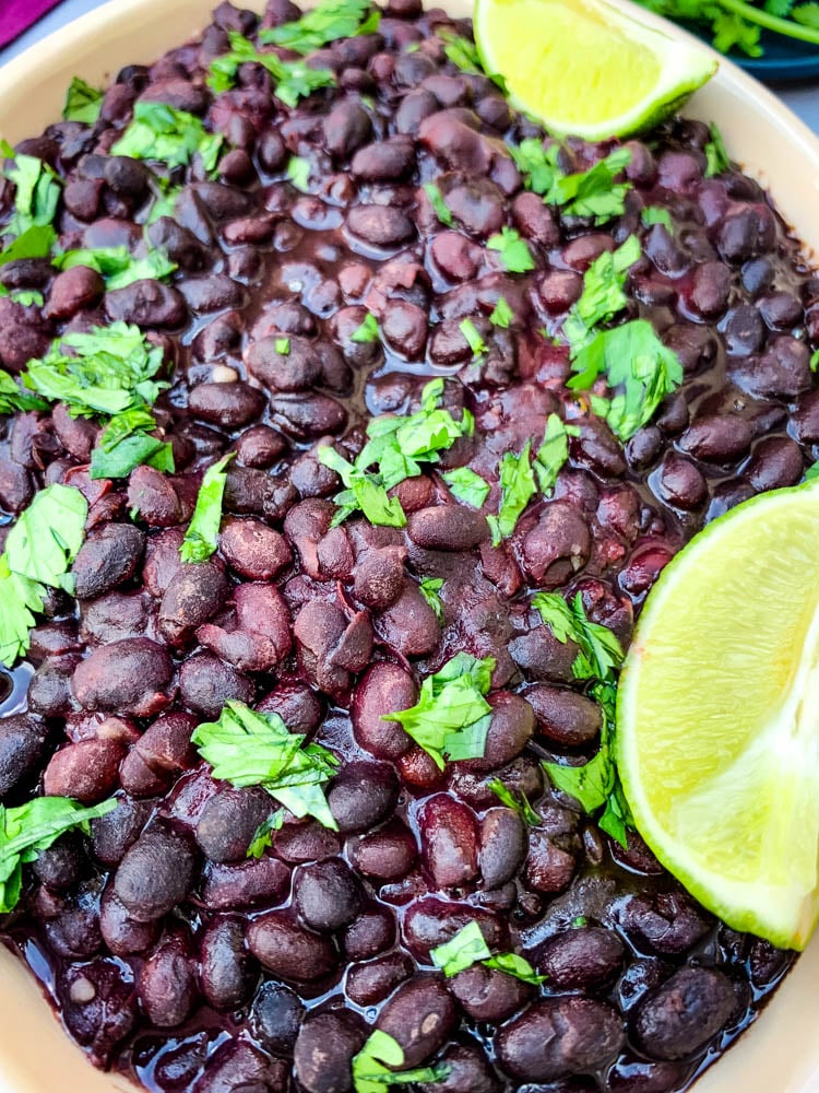 instant pot black beans in a blue bowl with cilantro and lime