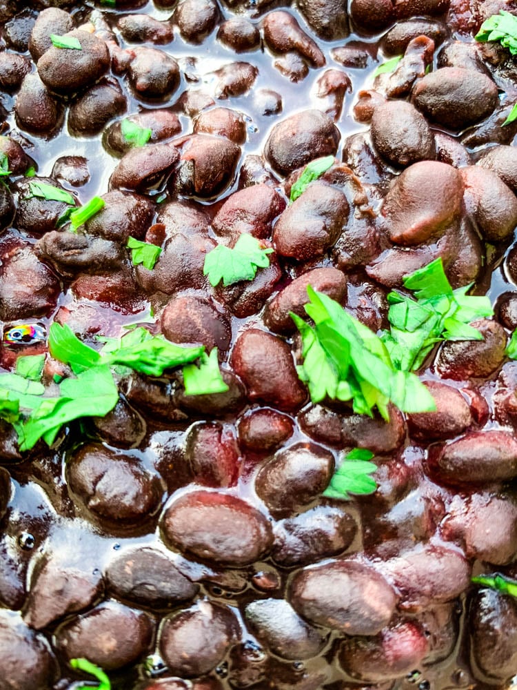 instant pot black beans in a blue bowl with cilantro and lime