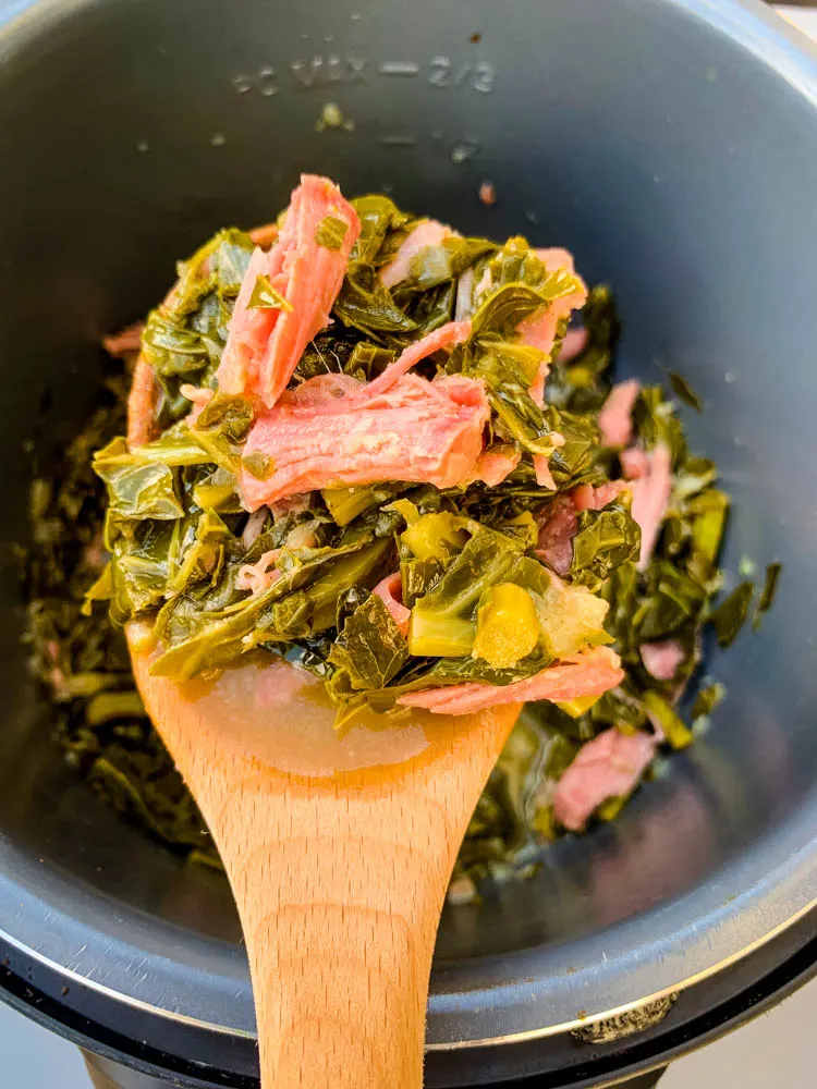 cooked collard greens in an Instant Pot with a wooden spoon