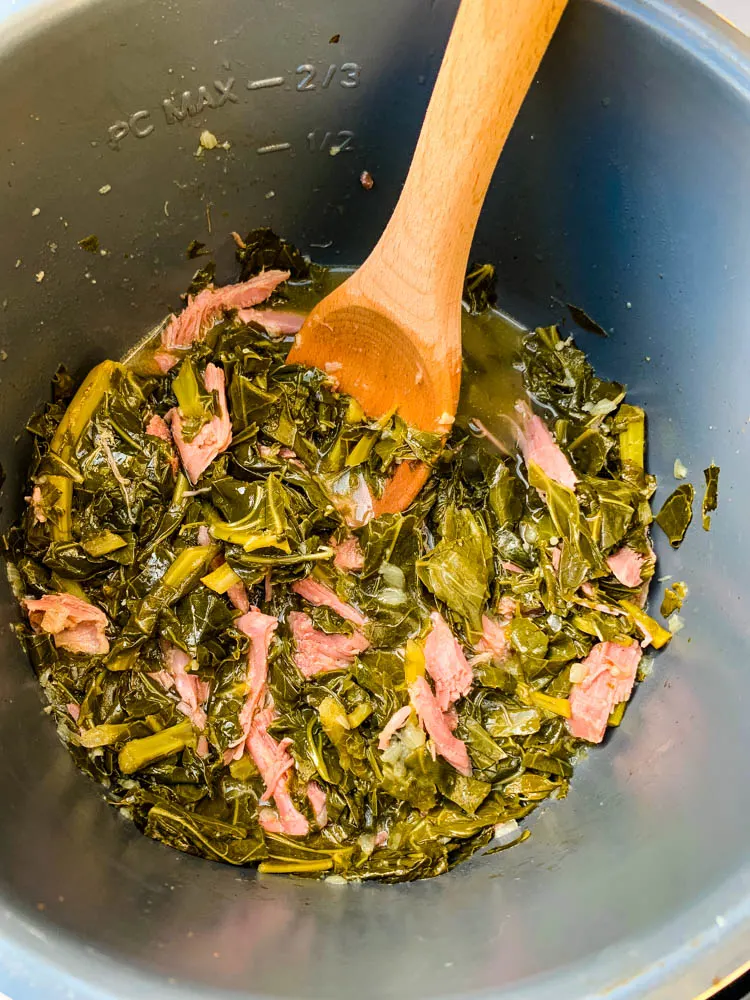 cooked collard greens in an Instant Pot with a wooden spoon