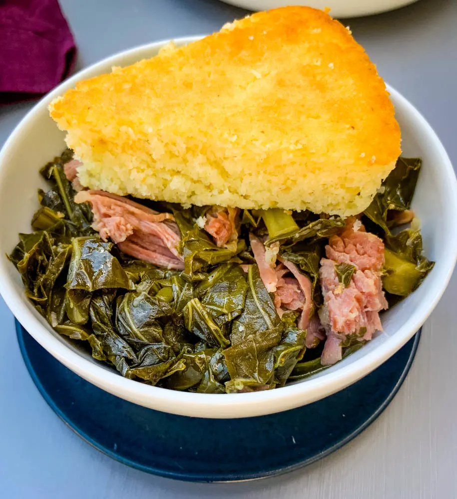 image of collard greens in a white bowl with cornbread